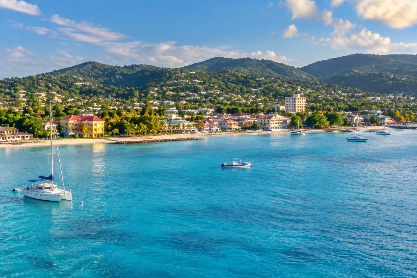 Illustration of a Caribbean waterfront with hills and boats